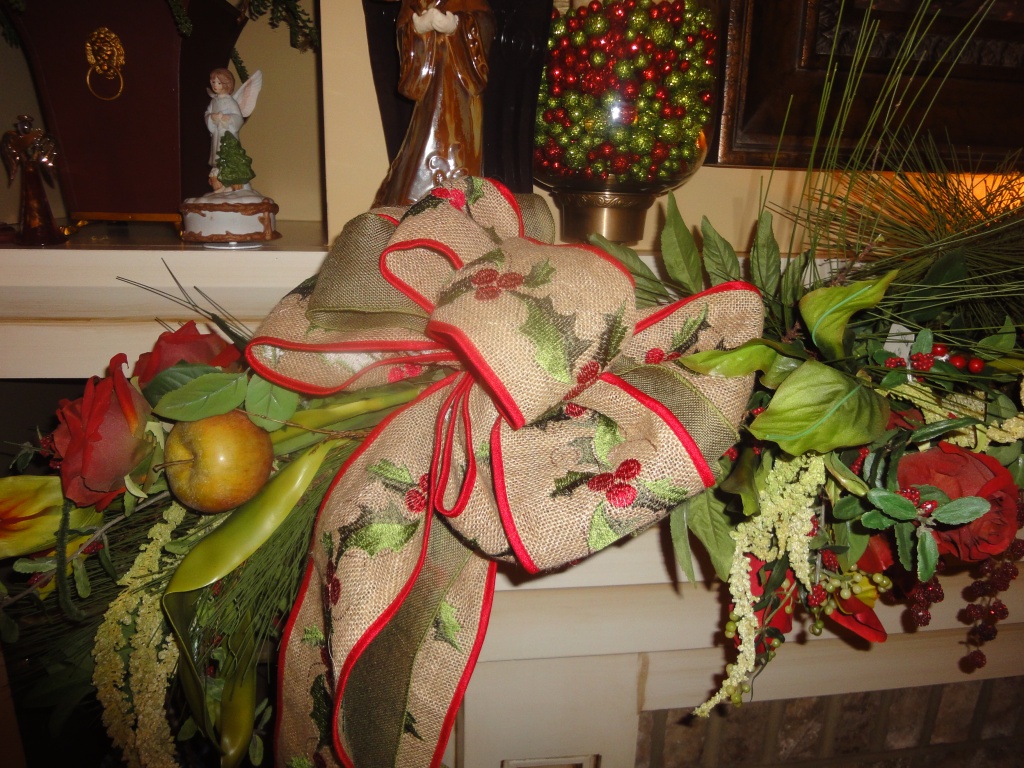 Burlap embroidered ribbon on a mantle along with flowers, fruits and traditional greenery